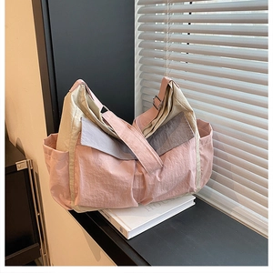 Detail of color-block nylon tote bag with wide strap and side pocket on window ledge