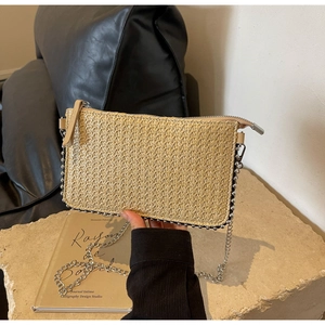 Detailed view of woven straw bag with metallic bead trim and silver chain strap