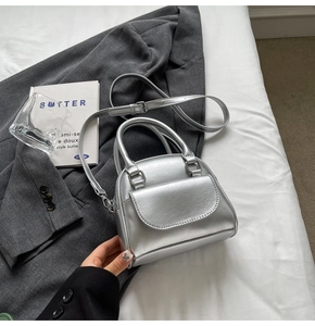 Detail of silver metallic mini handbag with rounded handles and adjustable strap