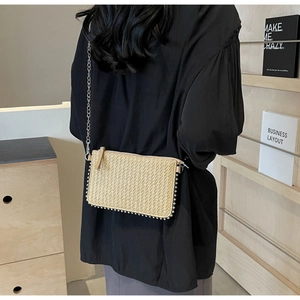 Detail of a natural straw crossbody bag with silver bead trim and metallic chain strap