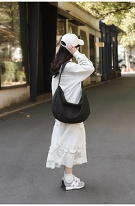 Detail view of large black crescent nylon shoulder bag on model for casual daily use