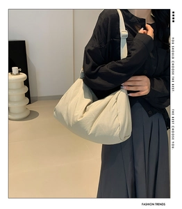 Detail van een crème gewatteerde crossbodytas met verstelbare riem gedragen door model
