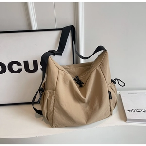 Detail of khaki canvas bag showing drawstring side pocket and black woven brand label