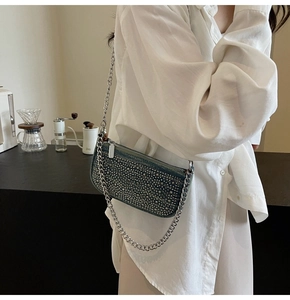 Detailed view of luxury rhinestone denim crossbody bag with a silver chain strap on a model