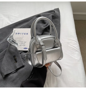 Close-up of a mini silver bowling handbag with metallic finish and detachable strap