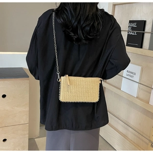 Detail of woven straw crossbody bag with silver bead trim and metal chain strap