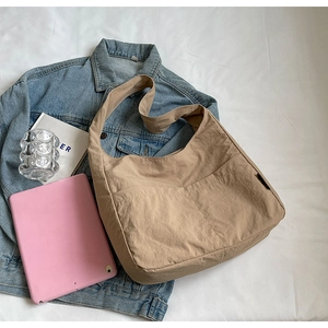 Spacious khaki nylon shoulder bag with divided front pockets shown on flat lay display