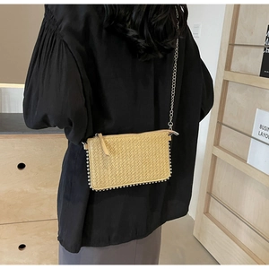 Detail of handwoven straw shoulder bag with metallic bead trim and chain strap