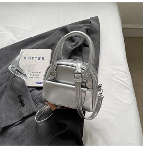 Detail of silver metallic Boston bag with smooth leather texture and crossbody strap