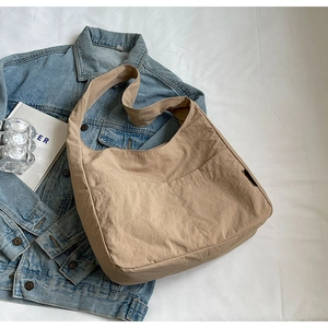 Detail shot of khaki large capacity shoulder bag with double front pockets on white fabric