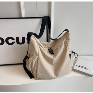 Detail of off-white large capacity nylon crossbody bag with black wide shoulder strap