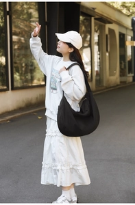 Close-up of a large black crescent nylon shoulder bag styled on a model for daily use