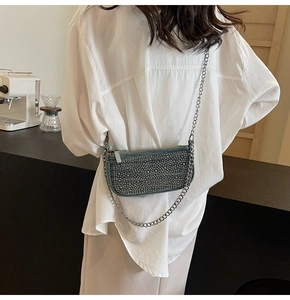 Detail of rhinestone denim crossbody bag with silver chain strap worn by a model