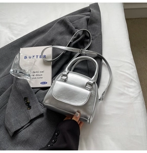 Macro shot of a silver metallic mini handbag resting on a grey blazer suit