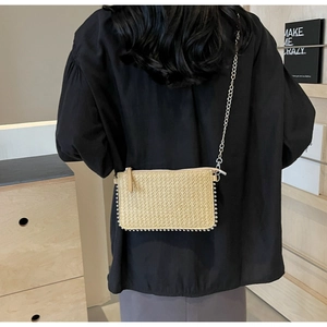 Detail of woven straw mini bag with silver bead trim and metal chain strap on model