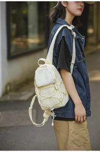 Scatto outdoor di uno zaino compatto in nylon color crema con lacci elastici esterni