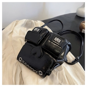 Close-up of black glossy leather backpack featuring silver chain and heart pocket detail