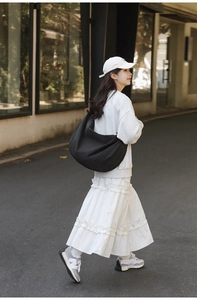 Detail of a black large capacity nylon shoulder bag shown in an outdoor street setting