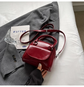 Miniature burgundy bridal handbag with silver hardware on elegant grey suit fabric