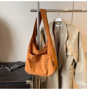 Detail of caramel nylon tote bag featuring two front pockets and wide shoulder straps