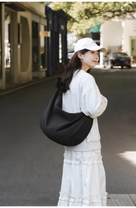 Detailed back view of a large black crescent nylon crossbody bag worn in a street setting