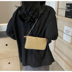 Straw crossbody bag with metal bead trim and silver chain strap shown on a model