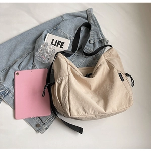 Detailed flat lay of a beige canvas crossbody bag with side drawstring and black strap