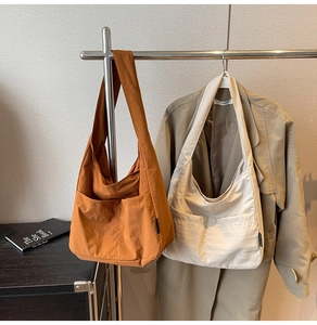 Detail of minimalist nylon tote bags with front pockets in caramel and cream colors