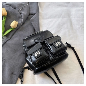 Close-up of black glossy leather backpack with heart patch and metal chain detail
