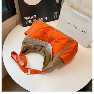 Detail of cargo crossbody bag with orange and khaki contrast stitching and metal buckle