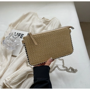 Detail of beige straw crossbody bag with silver beaded trim and chain strap