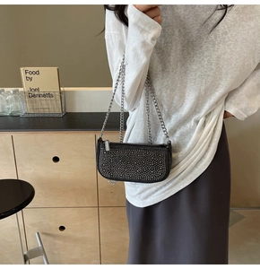 Close-up of black underarm bag with shimmering silver studs and sleek chain strap