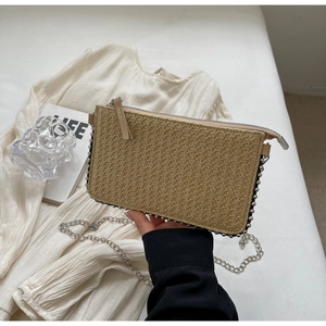 Detail showing the straw woven envelope bag texture with silver beaded trim and chain strap