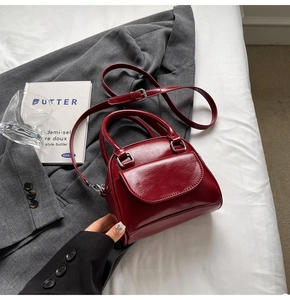 Detailed view of dark red leather handbag with silver metallic hardware and adjustable strap