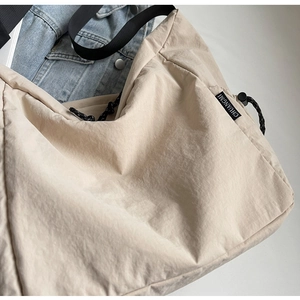 Detail of beige large canvas crossbody bag with adjustable wide black strap and drawstring