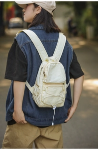 Mini zaino classico in nylon beige indossato da una modella in un contesto urbano