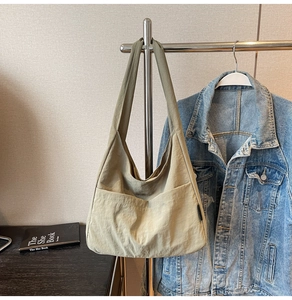 Detail of high-capacity khaki nylon tote bag showing front pocket and wrinkled texture