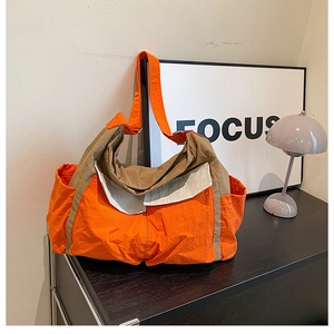 Detail of multi-color nylon messenger bag with orange, brown, and cream panels