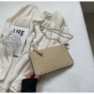 Detail of woven straw bag with silver bead trim and metallic chain strap for women