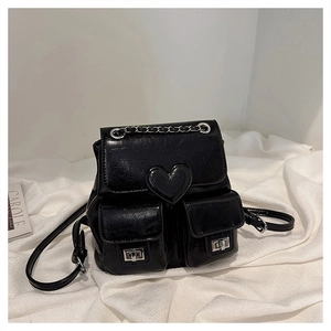 Detail of black glossy leather backpack with heart motif and silver metal buckles
