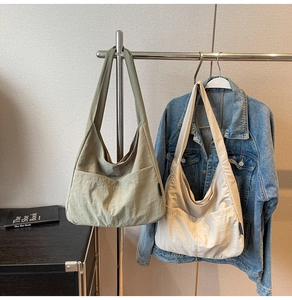 Detail view of large capacity canvas shoulder bags in green and cream with front pockets