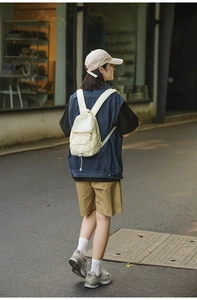Foto lifestyle di un mini zaino in nylon crema con dettaglio cordino elastico