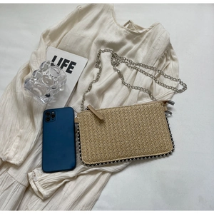 Detail of beige straw woven envelope bag with silver bead trim and metallic chain strap