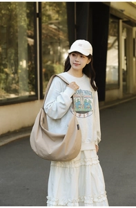 Detailed side view of a large beige nylon crescent bag with wide shoulder strap design