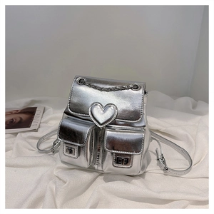 Detail of silver metallic mini backpack featuring heart patch and front flap pockets