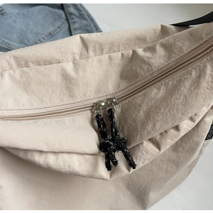 Close-up of durable canvas messenger bag with double zipper and woven cord pulls