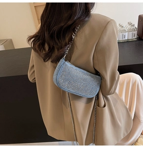 Detail of light blue rhinestone denim crossbody bag with silver chain strap on model