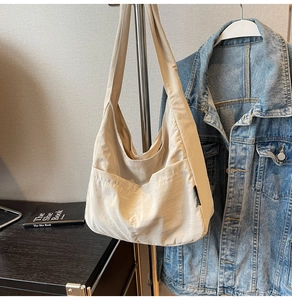 Close-up of beige minimalist hobo shoulder bag with large front pocket and soft texture