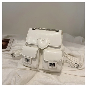 Detail of white glossy PU leather backpack featuring heart patch and silver twist locks