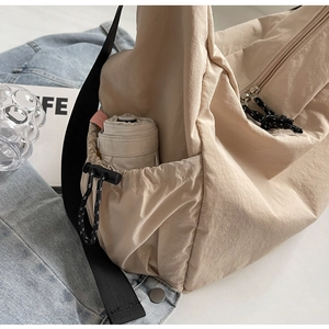 Detail of beige nylon tote bag featuring functional side drawstring pocket for umbrella